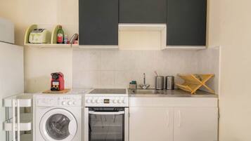 A compact kitchen with a washing machine, a stove, and a sink.