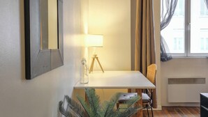 A small, well-lit room with a white table, a lamp, a chair, and a potted plant. - Charming with balcony in the heart of the 7th (Lyon)