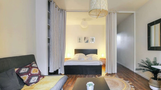 A modern hotel room with a bed, a sofa, a coffee table, and a potted plant. - Charming with balcony in the heart of the 7th (Lyon)