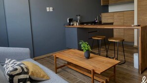 A compact kitchen with a central island, bar stools, and a wooden table with a plant. - Loft con balcón en la Americana | Lapso at Alarcón (Guadalajara)
