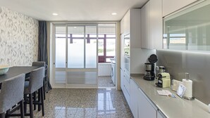 Een kleine keuken met een eethoek, een wasmachine en een koffiezetapparaat.