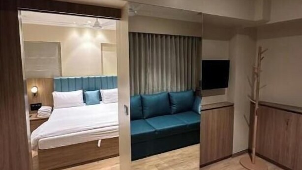 Une chambre d’hôtel moderne équipée d’un lit, d’un canapé, d’une télévision et d’un plancher en bois.