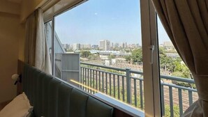 Une chambre d’hôtel avec une grande fenêtre, un lit et une vue sur le paysage urbain.