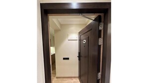 Un couloir avec une porte en bois, un interrupteur et un luminaire fixé au mur.