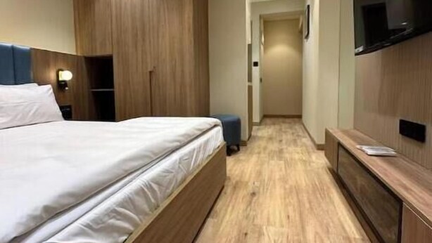 Une chambre d’hôtel moderne dotée d’un grand lit, de lambris en bois, d’un téléviseur à écran plat et d’un plancher en bois.