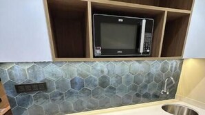 Une cuisine équipée d’un four à micro-ondes, d’un évier et d’un petit réfrigérateur.