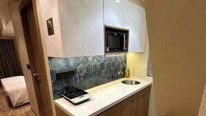 Una cocina compacta equipada con microondas, pileta y muebles de madera.
