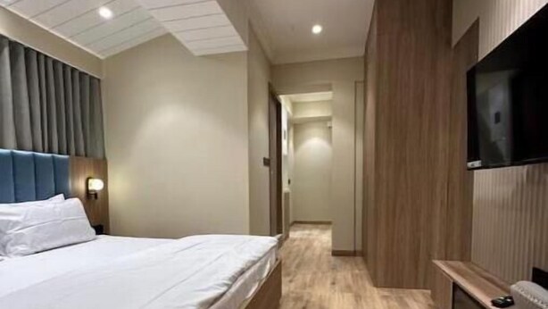 Una habitación de hotel moderna con una cama grande, un ventilador de techo, un televisor de pantalla plana y suelo de madera.