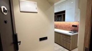 Un pasillo que conduce a una cocina moderna con armarios de madera y una encimera de mármol.