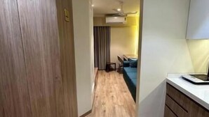Un pasillo estrecho con suelo de madera que conduce a un comedor con mesa y sillas.