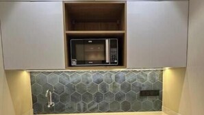 A compact kitchen with a microwave, a sink, and a refrigerator. - Skyline A : A Cozy Studio Apartment (Mumbai)