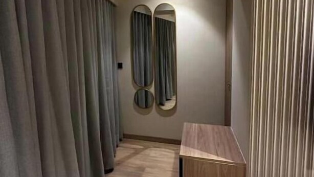 A hallway with a wooden floor, grey curtains, and a wooden bench. - Skyline A : A Cozy Studio Apartment (Mumbai)