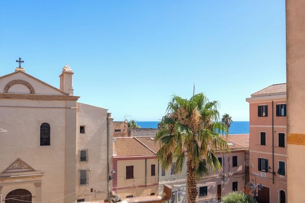 Un pueblo costero con edificios, una palmera y el mar al fondo.