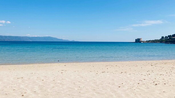 Ein Strand mit klarem, blauem Wasser und einem sandigen Ufer.