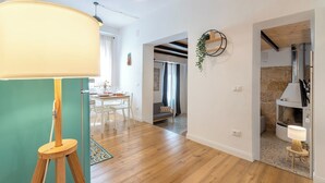 Ein modernes Wohnzimmer mit Holzboden, einem Essbereich mit Tisch und Stühlen, einer Wandpflanze und einem Kamin.