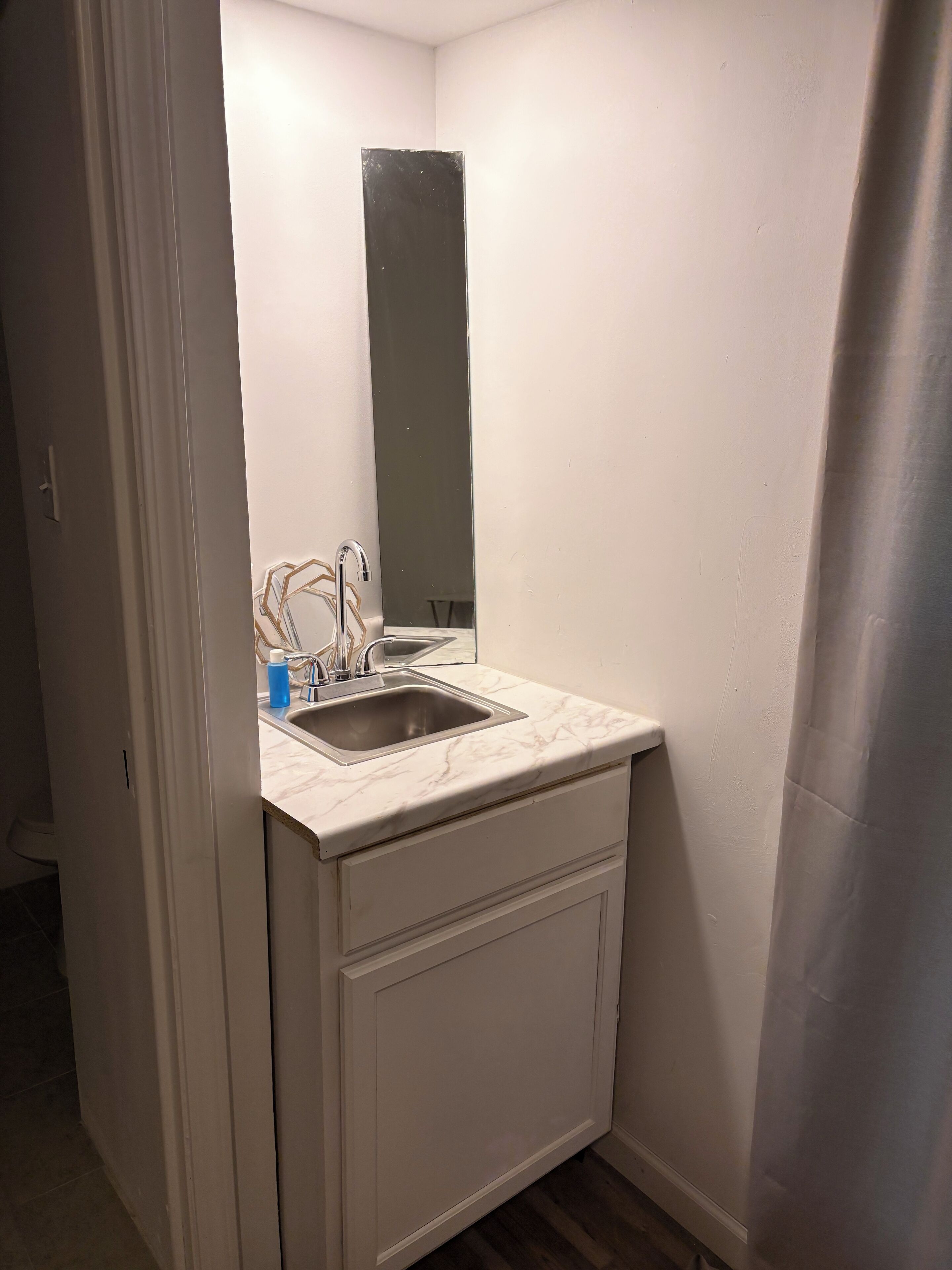 Une petite salle de bain blanche, avec un lavabo, un miroir et un meuble.