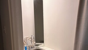 Un bagno piccolo e bianco con lavandino, specchio e mobiletto.