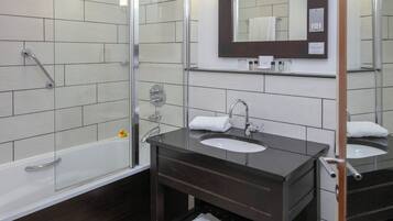 A modern bathroom with a glass shower enclosure, a vanity with two sinks, and a mirror above the vanity.