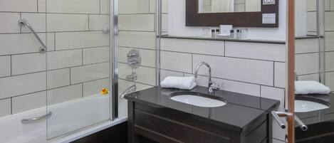 A modern bathroom with a glass shower enclosure, a vanity with two sinks, and a mirror above the vanity.