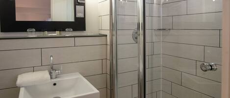 A modern bathroom with a sink, mirror, and glass-enclosed shower.