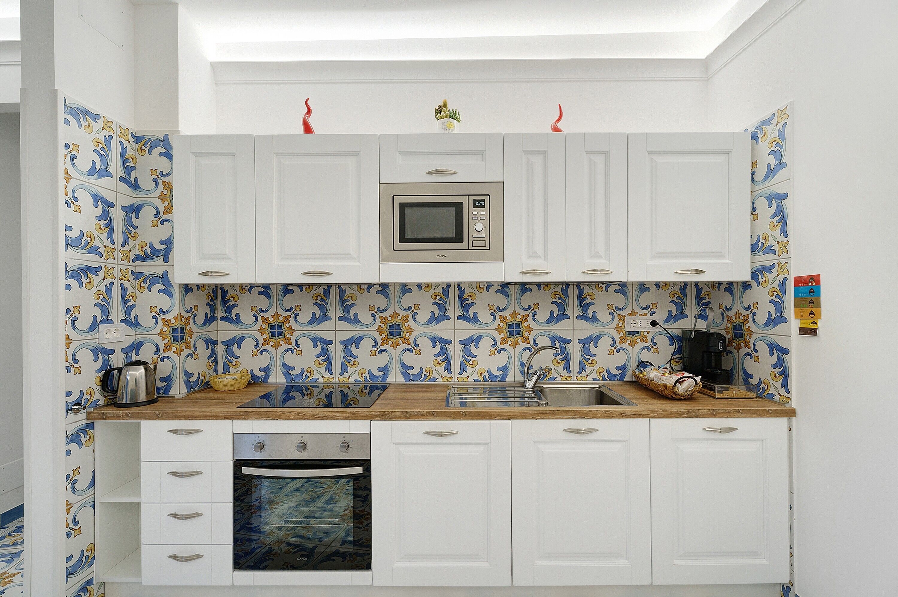 Une cuisine avec des meubles blancs, un four à micro-ondes, un évier et une cuisinière.