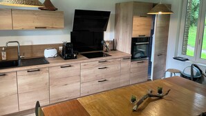 Une cuisine moderne avec des meubles en bois, un plan de travail noir, une machine à café et un four encastré.