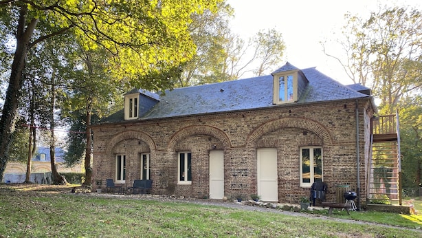 Un bâtiment en pierre doté d’un toit en pente, de fenêtres en arc de cercle et d’une petite tour.