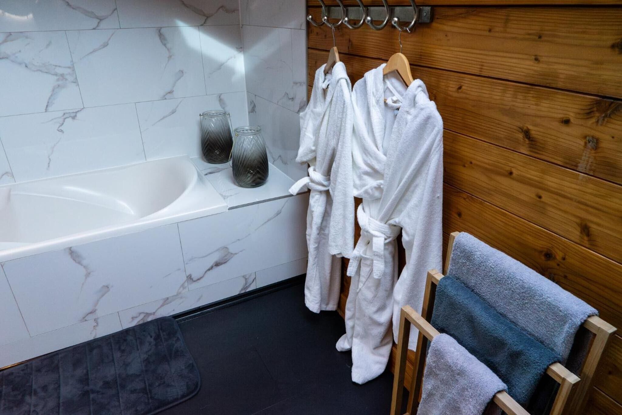 A modern bathroom with a marble sink, a bathtub, and wooden paneling.