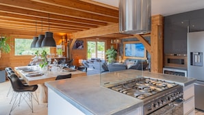 A modern kitchen with a central island, stainless steel appliances, and wooden beams. - Guesthouse 'Chambre Granon Au Datcha' with Mountain View, Private Terrace and Wi-Fi (Briançon)