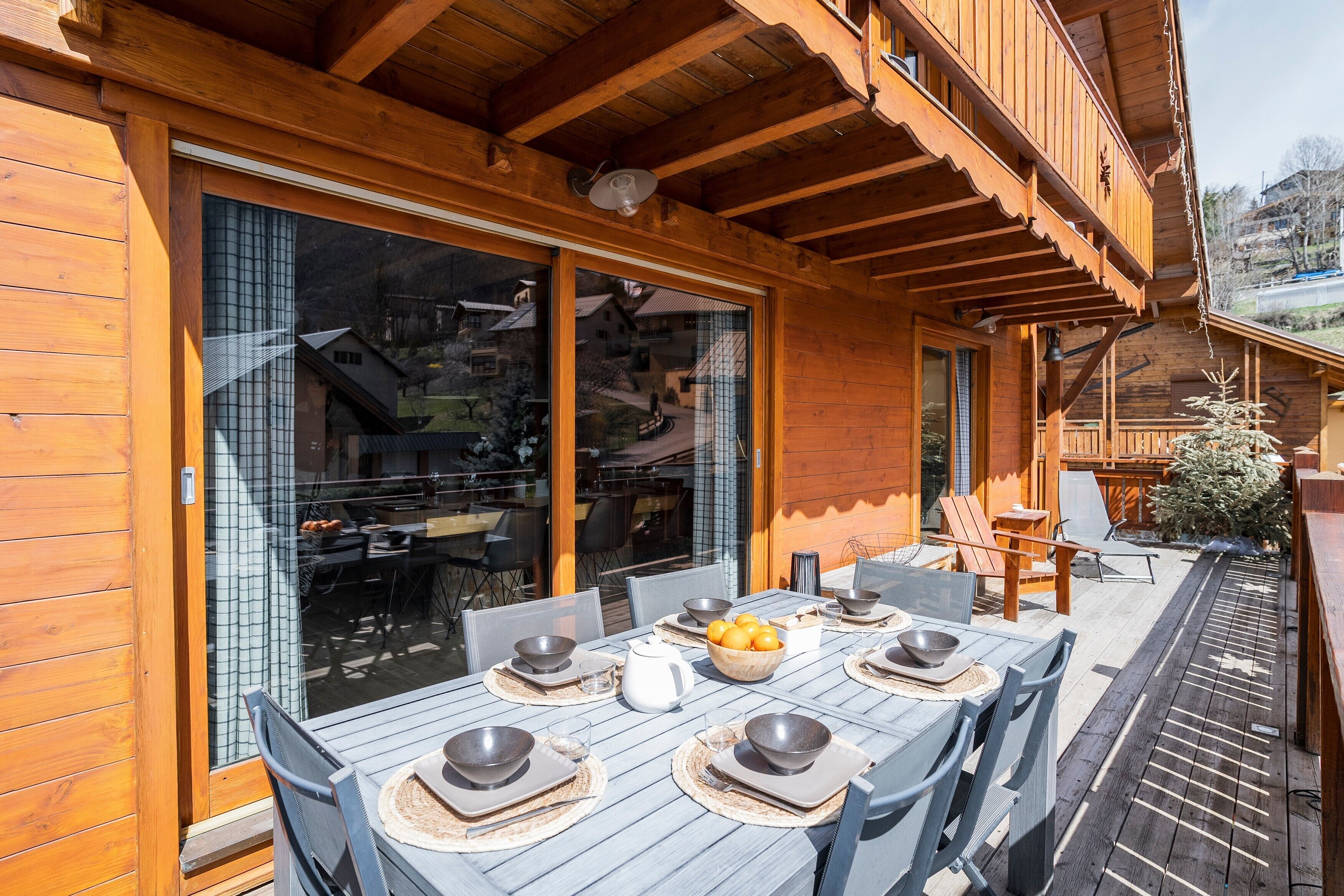 Une terrasse en bois avec une table à manger pour quatre personnes, entourée de chaises.