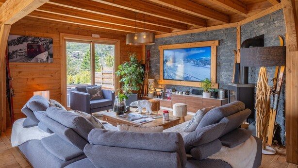 A cozy cabin interior with a fireplace, wooden beams, a large window, and a sofa. - Guesthouse 'Chambre Granon Au Datcha' with Mountain View, Private Terrace and Wi-Fi (Briançon)