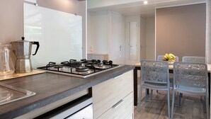 A modern kitchen with a gas stove, a coffee maker, and a dining area with a table and chairs.