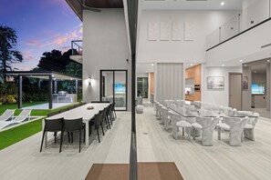 Un espace intérieur moderne comprenant un coin repas, une cuisine et un coin salon avec des chaises blanches.