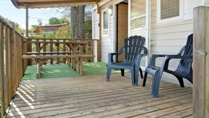 A wooden deck with a picnic table and two plastic chairs.