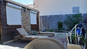 A patio with a wooden table and chairs, a small garden area with plants, and a wooden fence in the background. - Quiet location (Banyuls-sur-Mer)