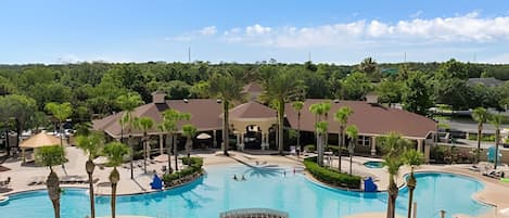 A resort with a large central pool, multiple buildings, and surrounding greenery.