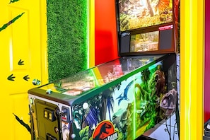 Une borne d’arcade sur le thème des dinosaures, dotée d’une façade en verre et entourée de murs jaune et rouge aux couleurs vives.