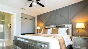 A modern hotel room with a large bed, two bedside tables, a ceiling fan, and a view of the hallway. - 6BD/4BA Windsor Luxury Villa | Game Room & Pool (Kissimmee)
