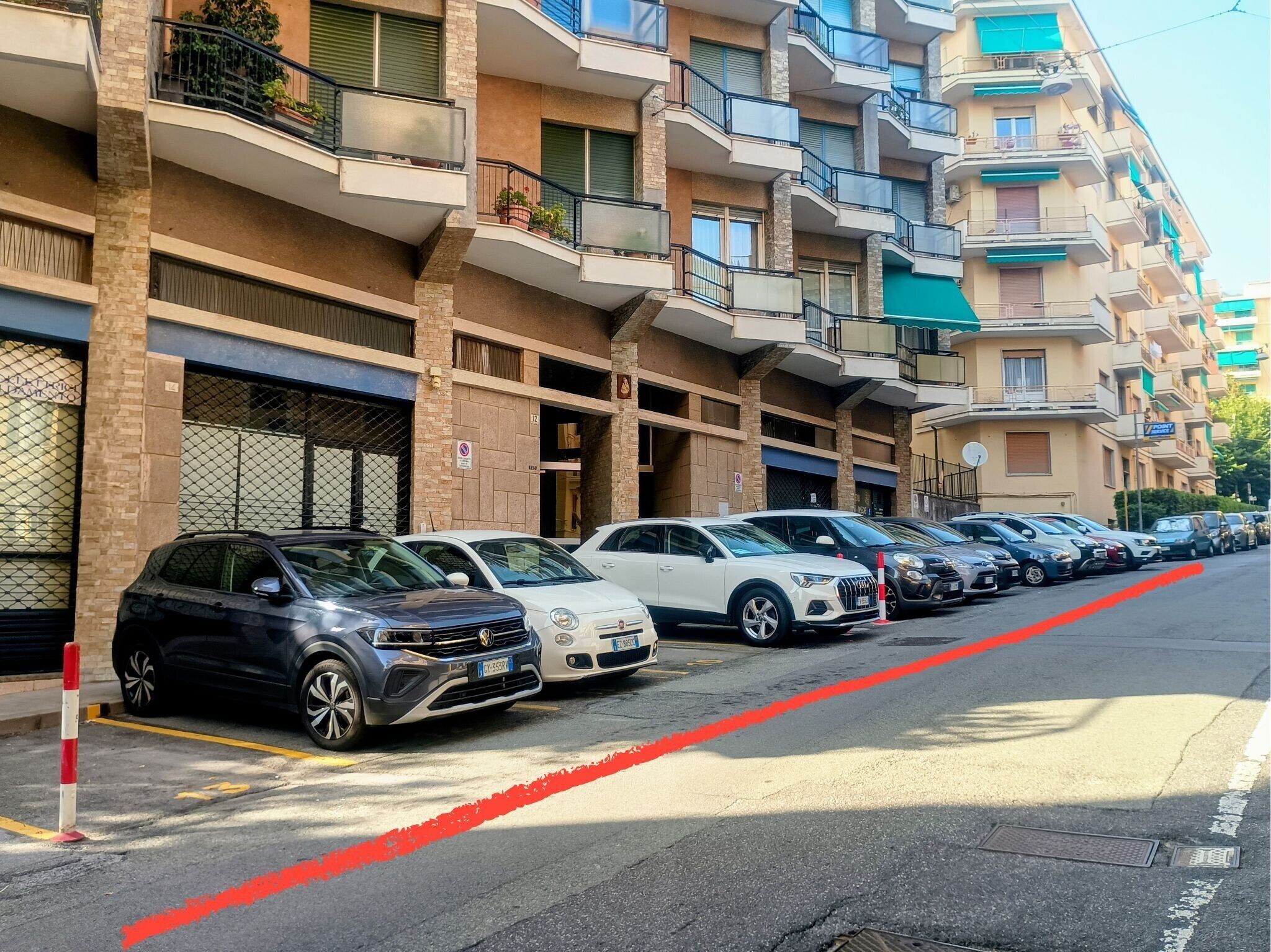 Een rij geparkeerde auto's voor een appartementencomplex met balkons.