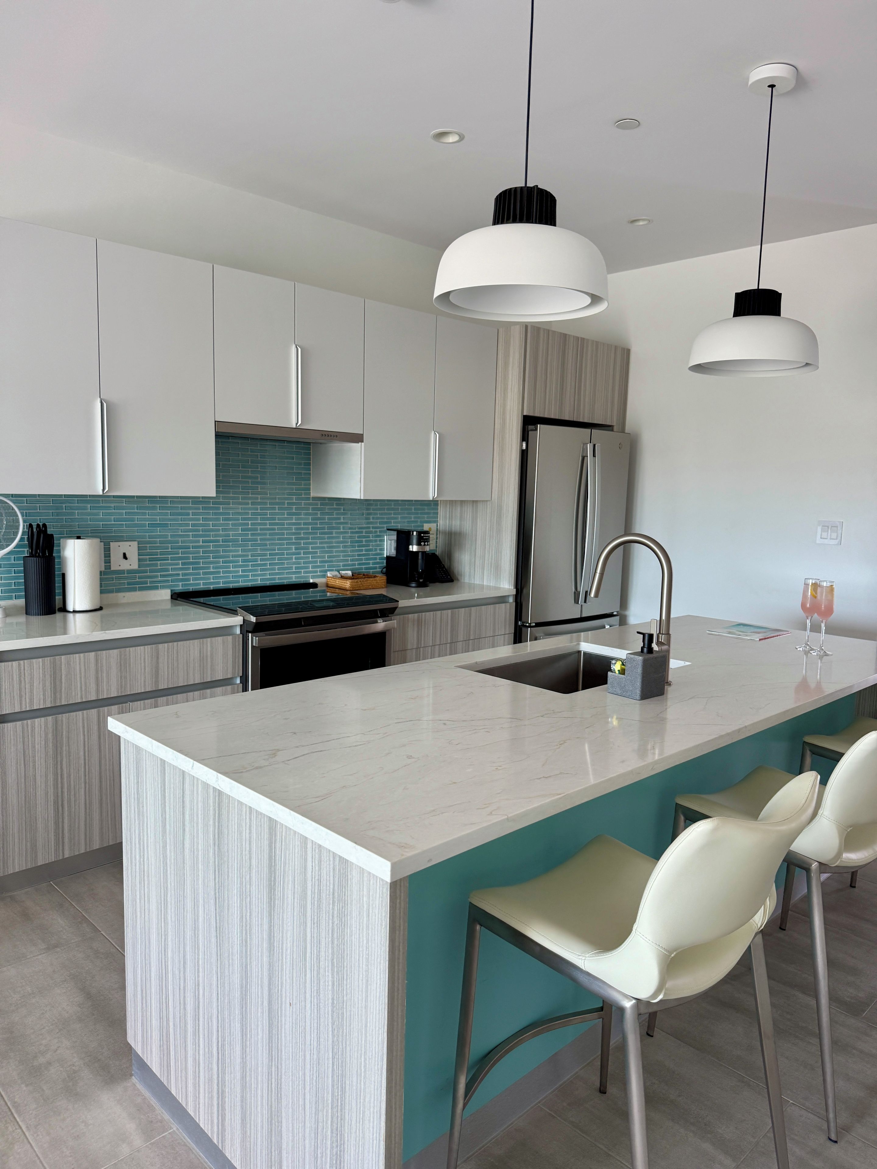 A modern kitchen with a central island, stainless steel appliances, and pendant lighting.