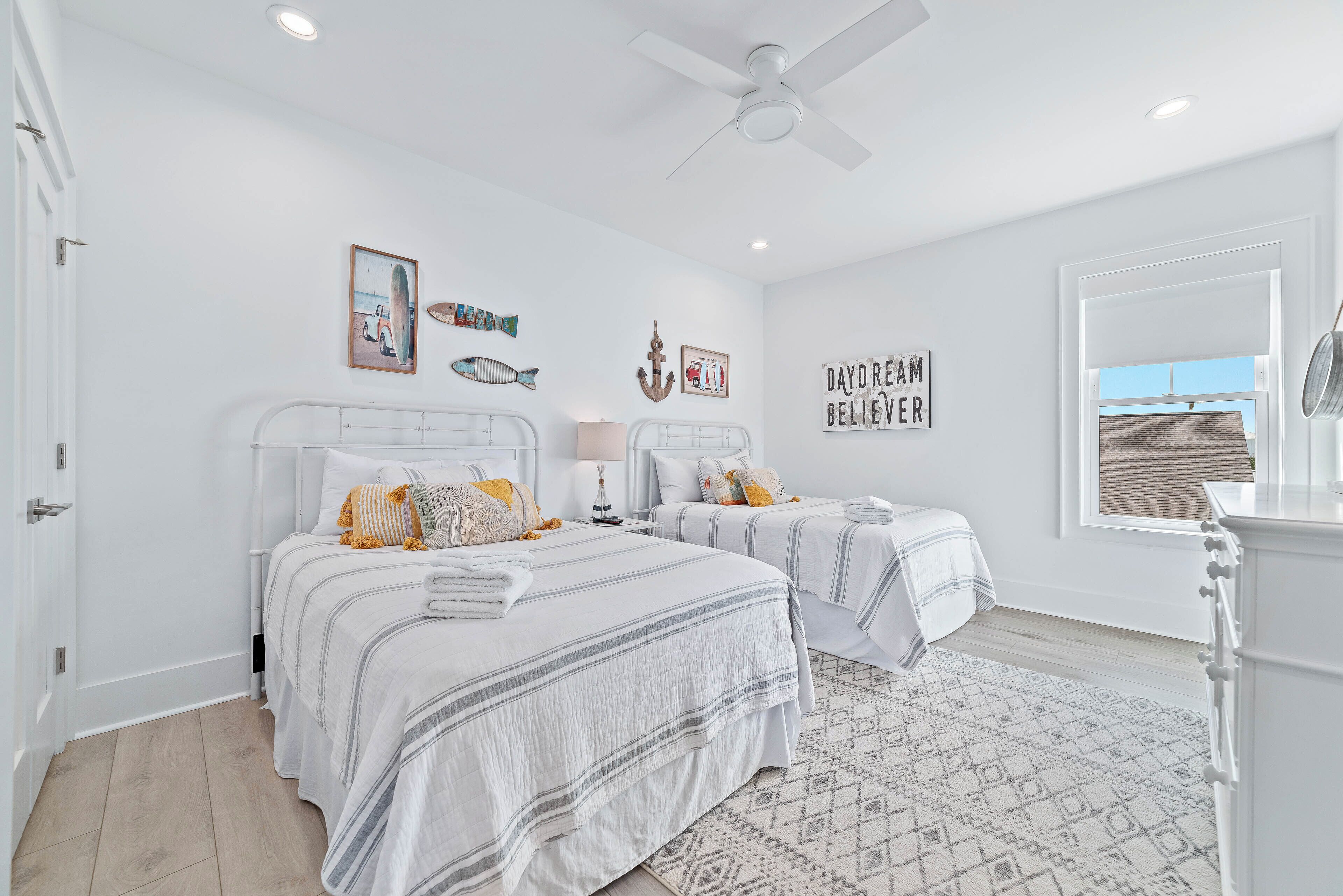 A bedroom with two beds, a ceiling fan, and a window with a view.