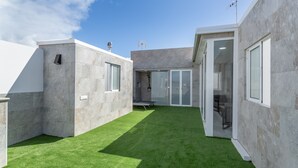 Een modern gebouw met een plat dak, een binnentuin met kunstgras en grote ramen.