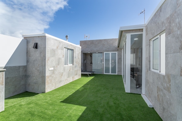 A modern building with a flat roof, a courtyard with artificial grass, and large windows.