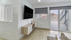 Een moderne woonkamer met een flatscreen televisie, schuifdeuren en een trap.