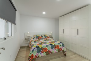 A bedroom with a bed, a wardrobe, a bedside table, and a window.