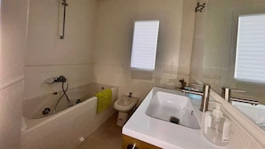 A bathroom with a bathtub, a sink, a mirror, and a window. - Rooms Carlos, next to Plaza Mayor (Madrid)