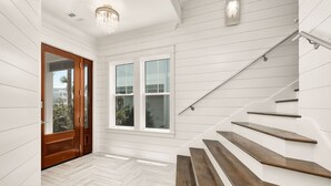 A modern interior with a wooden door, white walls, and a herringbone floor. - Grayton Gold|Easy Beach Access|Private Pool|Golf Cart (Santa Rosa Beach)