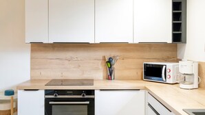 Una cocina moderna con armarios blancos, microondas, cafetera y encimera de madera.
