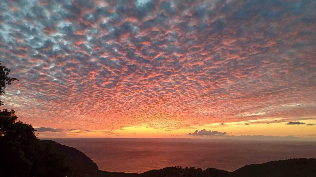 A sunset over a coastal landscape with a clear sky and distant land.