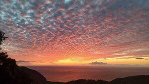 Un atardecer sobre un paisaje costero con cielo despejado y tierra a lo lejos.
